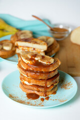 French toast with banana and homemade caramel with cinnamon, Breakfast dessert on a blue plate on a light background