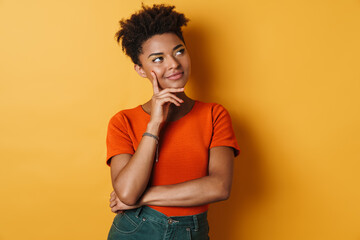 Image of pleased african american woman thinking and looking upward