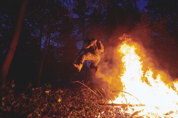 Soldier in Action at Night jumping over fire