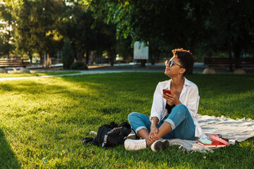 African woman sitting outdoors in park on a grass