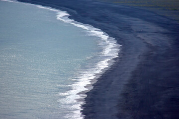 Waves of the Atlantic ocean fall on the black sand of the beach of Iceland from a height © photosaint
