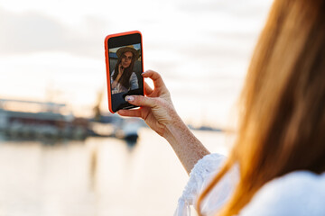 Image of happy ginger woman smiling and taking selfie on mobile phone