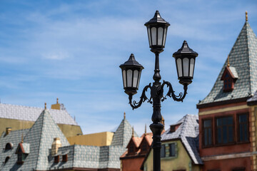 Fototapeta na wymiar Street lamppost against the old buildings background. Classic victorian street lamps on an old fashioned iron lamp post set