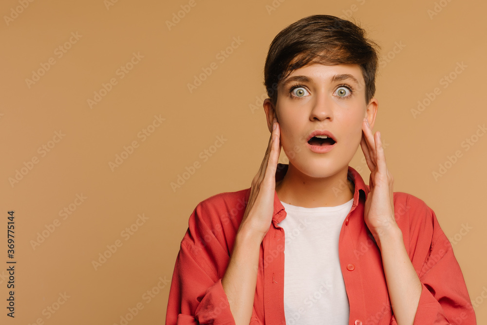 Wall mural close-up portrait of a surprised girl. beige background in a photo studio