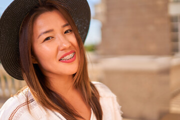Proud smile of a girl not embarrassed by braces, a girl of Asian appearance in a hat and white T-shirt
