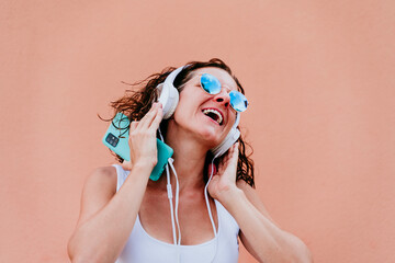 young happy woman outdoors listening to music on headset and mobile phone. Lifestyle at the city. Summertime. close up view