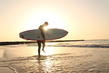 Fototapeta na wymiar Young man surfing at sunrise