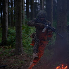 Fototapeta premium Soldier in Action at Night jumping over fire