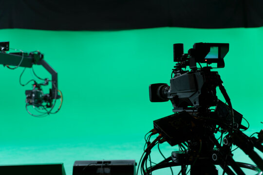 Professional Broadcast studio camera on crane and camera in virtual green studio room with sound equipment on the ceiling.