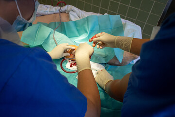 2 doctors perform a hematoma removal with sterile gloves on a lower leg