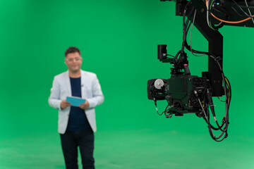 Broadcast television studio camera in greenscreen studio room with announcer on the ceiling.
