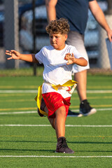 Obraz premium Cute athletic little boy playing excitedly in a flag football game