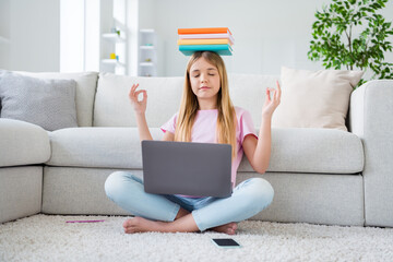Full size photo of focused little kid study remote laptop hold pile books lesson materials head meditate before online communication sit floor legs crossed folded in house indoors - obrazy, fototapety, plakaty