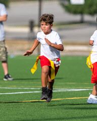 Obraz premium Cute athletic little boy playing excitedly in a flag football game