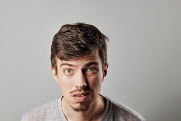 expression portrait of a handsome man with blue eyes and tiny beard. isolated over grey background....