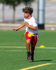 Obraz premium Cute athletic little boy playing excitedly in a flag football game