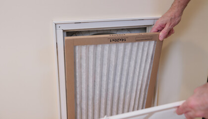 Replacing dirty central air conditioning  air filter.  HVAC repair technician performing...