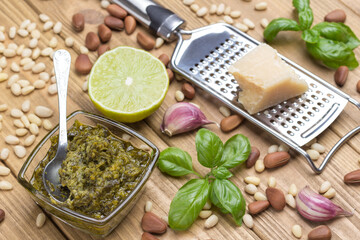 Basil leaves, olive oil, parmesan on grater, garlic, pine nuts. Pesto sauce cooking