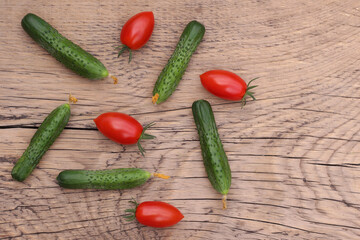 fresh cucumbers and red cherry tomatoes on vintage wooden background, top view