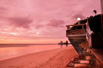 Scenic view of a tropical pink sunset on the beach of Anse Reunion in La Digue Island with the resort structure on side. Seychelles