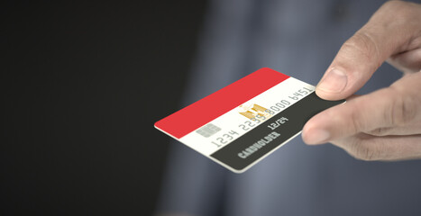 Man offers plastic bank card with printed flag of Egypt, close-up shot. Fictional numbers