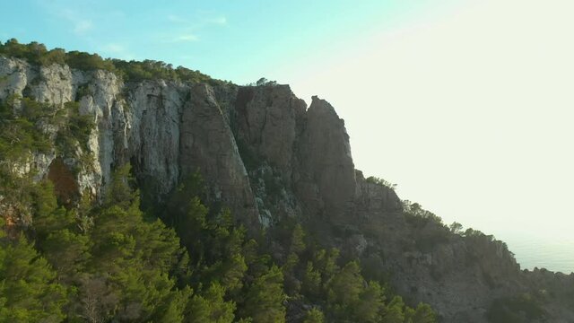 Group of friends watching the sunset from the top of a cliff overlooking the sea.