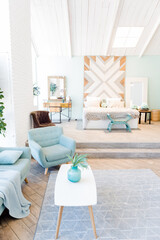 Fashionable spacious apartment with a stylish design in green, grey and white pastel colors with big window and decorative walls. bedroom and kitchen space