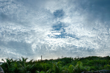 Cloudscape with dramatic overcast sky with sunlight over a tropical land