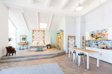 Fashionable spacious apartment with a stylish design in green, grey and white pastel colors with big window and decorative walls. bedroom and kitchen space