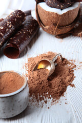 Cocoa powder with a vintage scoop on a white background.The chocolate pastille is rolled up in the form of a tube with a coconut on a white background. Copy of the space.