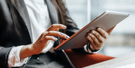 Businesswoman at her workplace reads information on a tablet. A woman works with documents and searches for insights on the Internet. The girl is thinking about the idea  in the office.