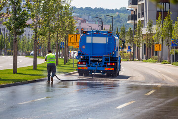 Worker cleaning and disinfects the streets with water truck