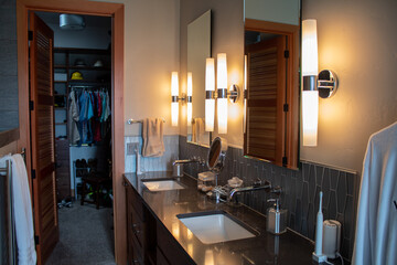 A modern bathroom vanity with a large walk-in closet and granite counters.