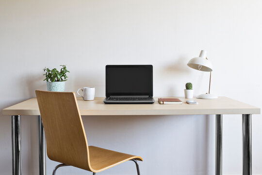 Wooden desk with chair laptop plants and lamp
