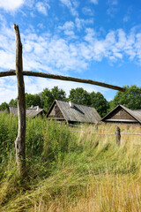 Fototapeta na wymiar old abandoned village landscape with wooden houses and well crane under blue sky