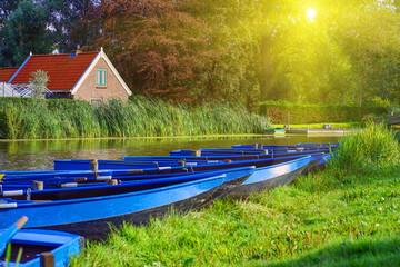 Landscape with blue wooden boats on the river. A row of boats by the river in the morning. Blue...