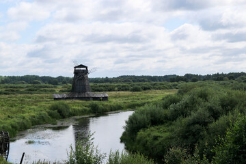 old abandoned wooden windmill in the field by the river