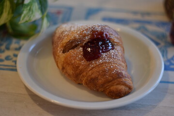 Un corazon de frambuesa dulce dentro de un croissant .