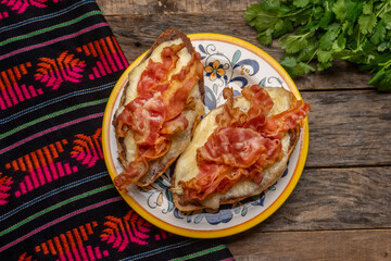 Mexican molletes with bacon on wooden background
