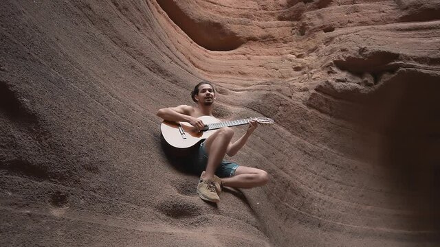 joven m&uacute;sico canta y toca la guitarra dentro de Temisas Canyon. Aguimes. Gran Canaria
