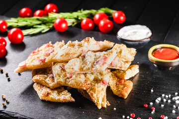 Traditional Italian focaccia among tomato and spices on a dark background, studio light. Traditional food concept