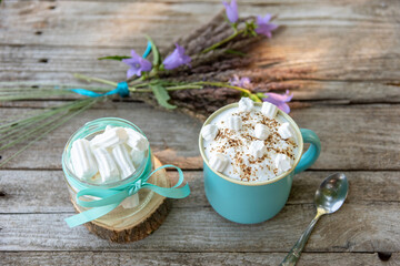 Hot cappuccino with marshmallows and foam in a light blue Cup with flowers.