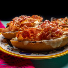 Mexican molletes with bacon and pico de gallo sauce on turquoise background