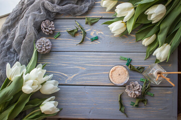 White tulips and candles on a blue wooden background. Top view with copy space.