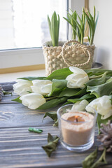 White tulips and candles on a blue wooden background. Top view with copy space.