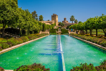 Ornamental pools sparkle beneath medieval towers in Cordoba, Spain in the summertime