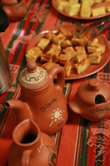 Three small clay teapots with on the background little snacks of a buffet