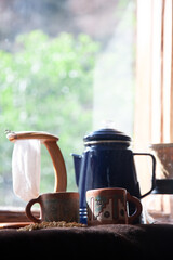 Two coffee cups, a coffee kettle and a filter: all the required equipment for a coffee table