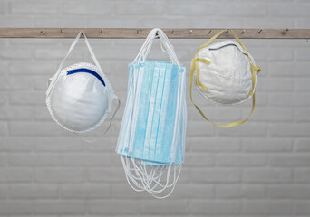 Different colored medical masks hanging in front of brick wall