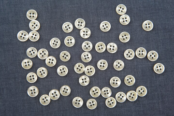 Plastic shiny buttons for clothes on a fabric background. Fashion and clothing. Factory industry.